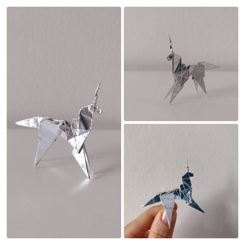May include: Three origami unicorns made from silver foil paper. The unicorns are in different poses, with one standing on a hand.