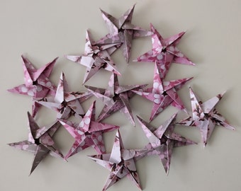 May include: A collection of 12 pink and white origami stars with a floral pattern. The stars are arranged in a cluster, with some overlapping.