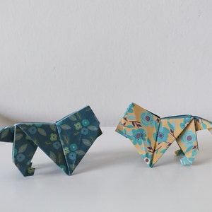 May include: Two origami cats made from patterned paper. One cat is blue and green with a floral pattern. The other cat is yellow and blue with a floral pattern.