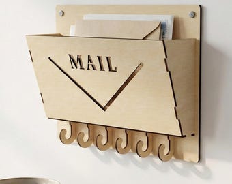 Peut inclure: Organisateur de courrier en bois clair avec une fente pour le courrier et le mot "MAIL" découpé. Il comprend sept crochets en dessous pour les clés. L'organisateur est monté sur une planche de bois rectangulaire.