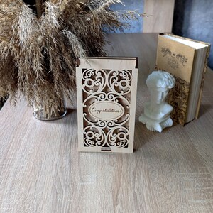 May include: A wooden box with a decorative cutout design and the words "Congratulations!" engraved on the front.