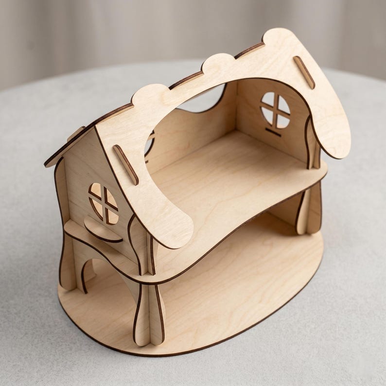 A wooden laser cut model of a house, likely made of wood, sitting on a surface.