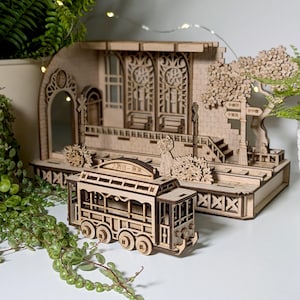 Puede incluir: Un modelo de madera de una estación de tren con un pequeño vagón de tren de madera. La estación tiene una fachada detallada con ventanas y un letrero que dice "大都市 - 車站". El vagón es un tranvía con un letrero que dice "大都市 - 車站".