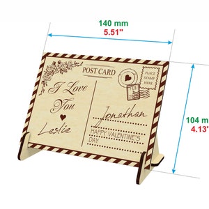 May include: A wooden postcard stand with a vintage design. The postcard features the text "I Love You" and "Happy Valentine's Day". The stand is 140 mm wide and 104 mm tall.