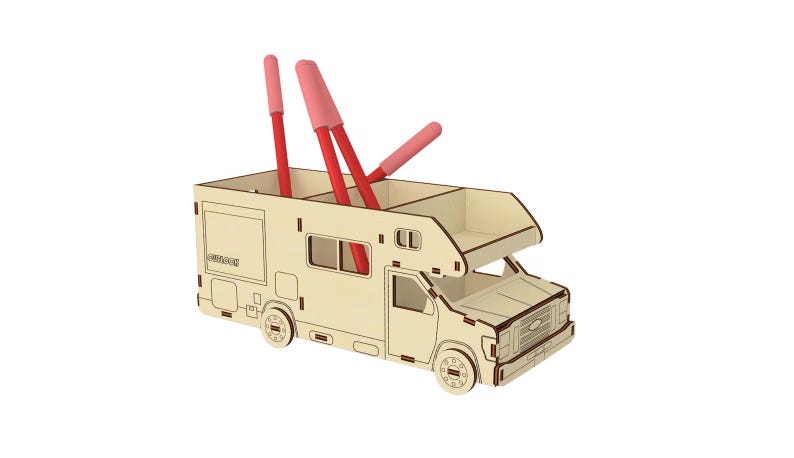 May include: A wooden desk organizer shaped like a camper van with three red pens sticking out of the top. The camper van is light brown with a white roof and windows.