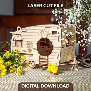 May include: A light-colored wooden laser-cut model of a vintage camper trailer featuring engraved details of two birds, a flower vase, and a window. The structure includes a small ladder and a circular opening. Text reads LASER CUT FILE and DIGITAL DOWNLOAD.