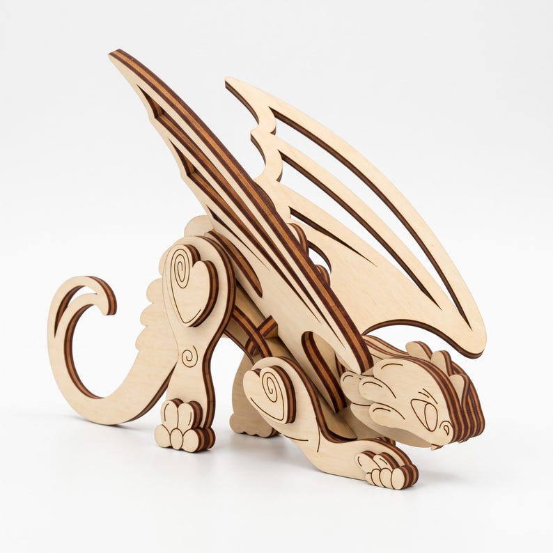 3D laser cut plywood fantasy dragon figurine with large wings and curled tail standing proudly on seamless white background.