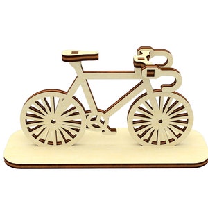 May include: A wooden model of a bicycle with a brown base. The bicycle is made of light wood and has a simple design.