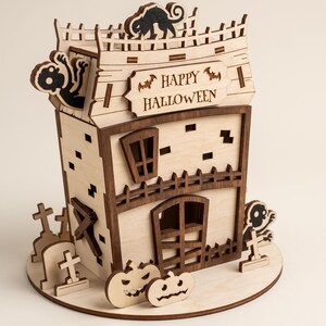 Detailed view of a laser cut plywood zombie house for Halloween, featuring a black cat and "Happy Halloween" sign.