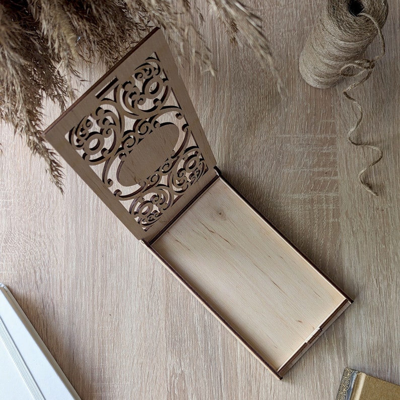 May include: A wooden box with a decorative, intricate, laser-cut design on the lid. The box is open and the inside is empty.