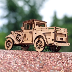 May include: A wooden model of a vintage pickup truck with a brown wood finish. The truck has a flatbed and a detailed interior.
