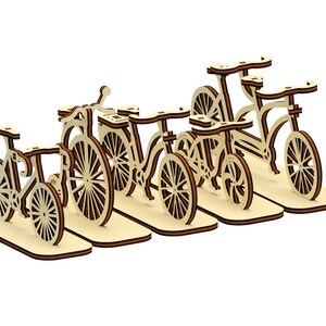 May include: A set of five wooden bicycle figurines, each with a unique design and color. The figurines are arranged in a row, with the largest one on the left and the smallest one on the right. The figurines are made of light wood and have a natural finish.