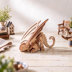 a wooden dragon toy sitting on a wooden surface, surrounded by various small items such as a miniature house, a rocking horse, and some books.
