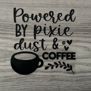 Op de afbeelding: Zwart-wit grafisch ontwerp met de tekst "Powered by pixie dust & coffee" met een zwarte koffiekop en een klein blaadje.
