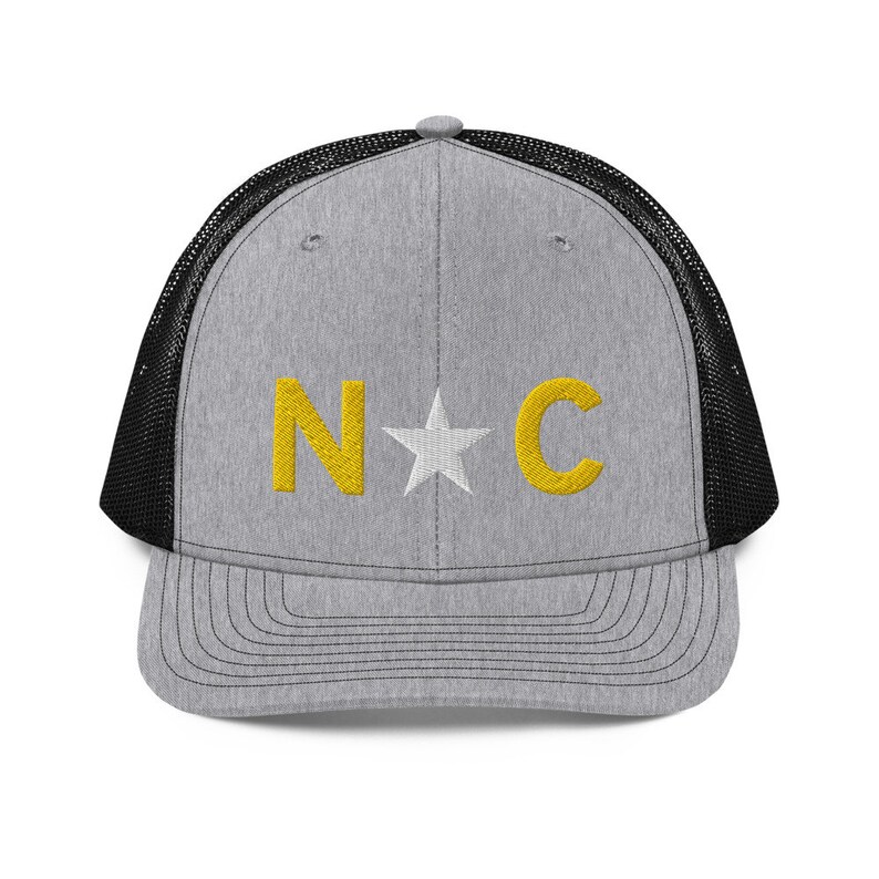May include: A gray and black trucker hat with a white star and the letters "N*C" embroidered in yellow.
