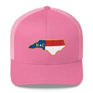 May include: Pink trucker hat with a white mesh back. The hat features an embroidered outline of the state of North Carolina with the state flag colors and the letters "N*C" in the center.