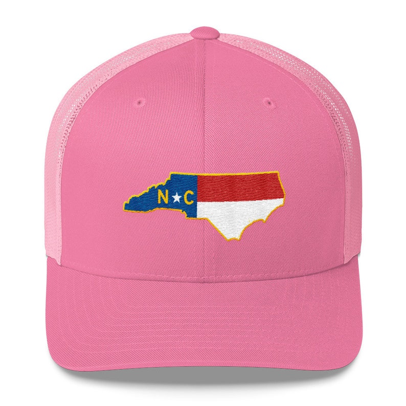 May include: Pink trucker hat with a white mesh back. The hat features an embroidered outline of the state of North Carolina with the state flag colors and the letters "N*C" in the center.