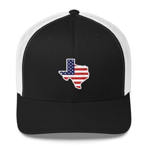 May include: A black and white trucker hat with a white mesh back. The front of the hat features an embroidered image of the state of Texas with the American flag design.