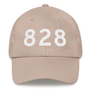 Puede incluir: Una gorra de béisbol beige con el número 828 bordado en blanco en la parte delantera.
