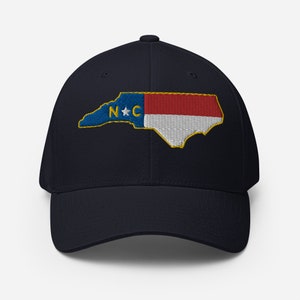 May include: A navy blue baseball cap with an embroidered North Carolina state outline and flag. The flag features red, white, and blue stripes with a yellow star and the letters "N.C."