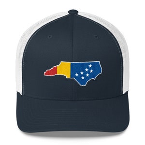 May include: A navy blue and white trucker hat with an embroidered outline of the state of North Carolina, filled with the colours of the North Carolina state flag.