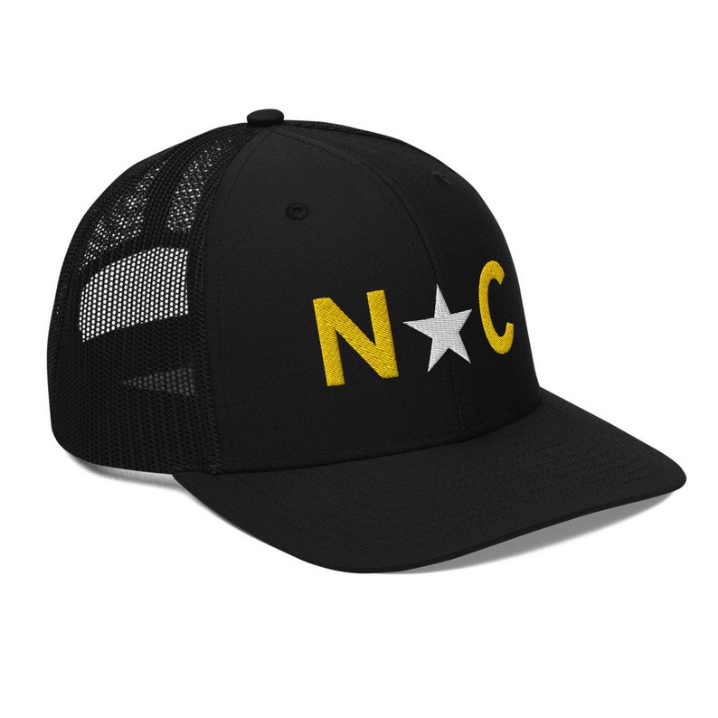 May include: Black trucker hat with a yellow embroidered "N*C" logo. The star in the logo is white.
