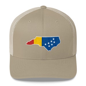 May include: A beige and white trucker hat with an embroidered outline of the state of North Carolina, filled with the colours of the North Carolina flag.