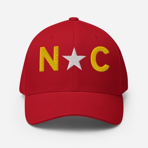 May include: A red baseball cap with a white star and the letters "N*C" embroidered in yellow.