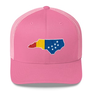 May include: Pink trucker hat with a mesh back. The hat features an embroidered design of the state of North Carolina with the colours of the Romanian flag.