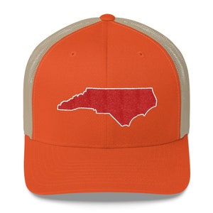Pu&ograve; includere: Un cappello da camionista con una parte posteriore in rete color beige e un pannello anteriore arancione. Il pannello anteriore presenta un contorno ricamato rosso dello stato della Carolina del Nord.