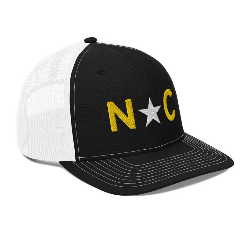 May include: Black and white trucker hat with a gold embroidered "N*C" logo.