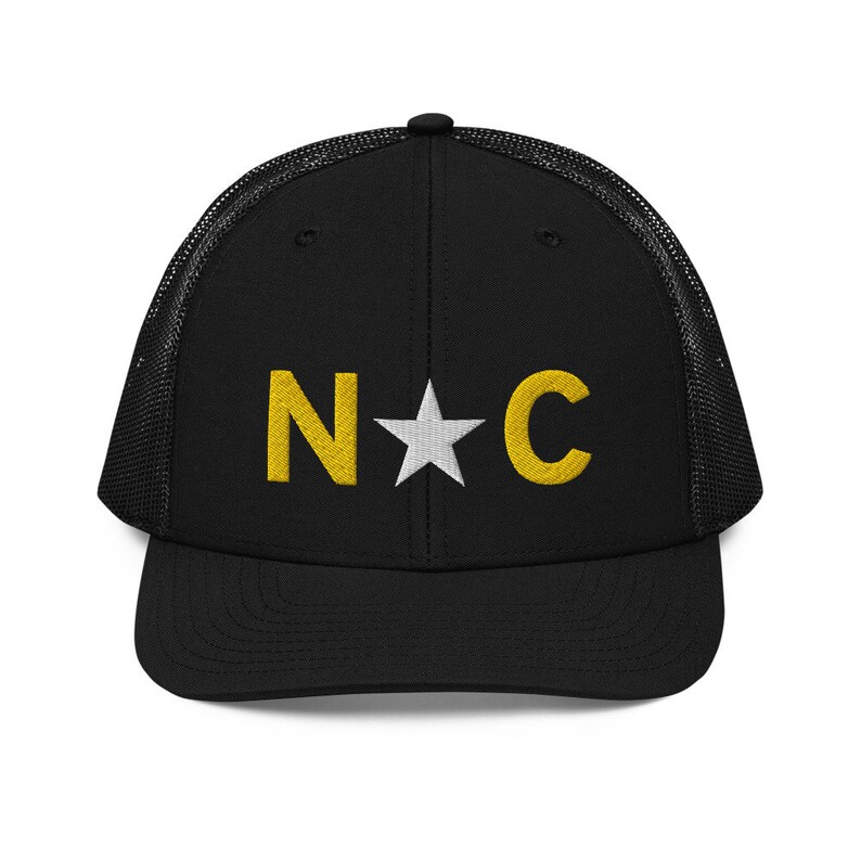 May include: Black mesh trucker hat with a white star and the letters "N*C" in yellow embroidery.