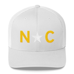 May include: White trucker hat with a yellow embroidered "N*C" design. The star is white.