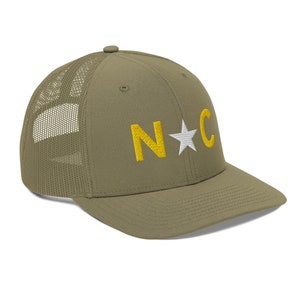 May include: A green and white trucker hat with a yellow embroidered "N*C" on the front.