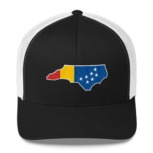 May include: A black and white trucker hat with a mesh back. The front of the hat features an embroidered outline of the state of North Carolina with the state flag colours inside.