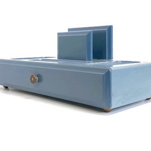 May include: A light blue wooden desk organizer with a drawer and two compartments. The organizer has a small brass knob on the drawer.
