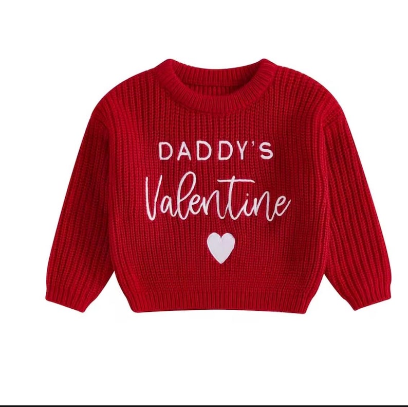 May include: A red knit sweater with long sleeves. The sweater features the text "DADDY'S Valentine" in white script, along with a white heart graphic. The sweater is designed for children.