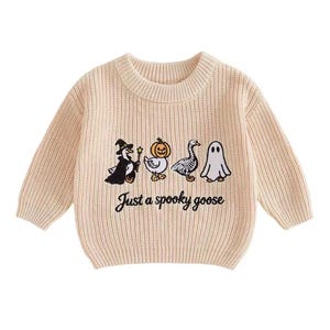 May include: A beige long-sleeve crewneck sweater featuring a ribbed knit texture. The front displays an embroidered graphic of four geese in costumes, including a witch, a pumpkin, a skeleton, and a ghost, with the text Just a spooky goose.