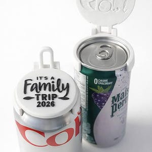May include: Two white can covers with handles, one on a Coca-Cola can and the other on a green can. The Coca-Cola can cover reads "IT'S A Family TRIP 2026". The other cover reads "Opal Owl".