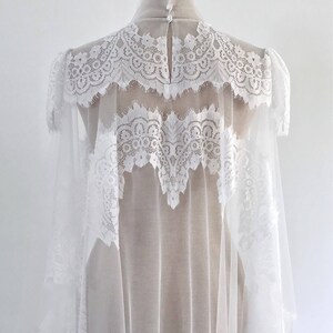 May include: White lace bridal veil with a sheer tulle base. The veil has a scalloped edge and is decorated with delicate lace patterns.