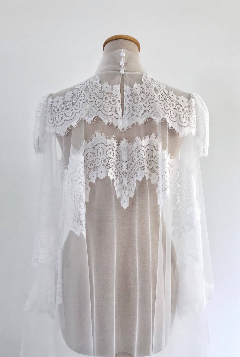 May include: White lace bridal veil with a sheer tulle base. The veil has a scalloped edge and is decorated with delicate lace patterns.