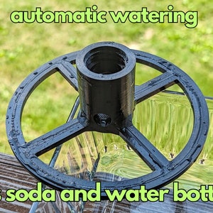 May include: Black plastic automatic watering device that fits soda and water bottles. The device has a round base with a center post and four spokes.