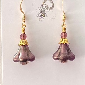 Purple glass beads shaped like flowers atop champagne colored glass crystals with gold plated bead caps on gold plated ear hooks