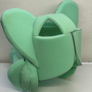 May include: A green foam head form with two large ears, a cut-out for the face, and markings for sewing.