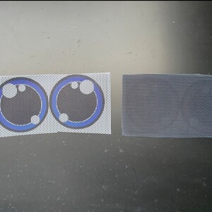 May include: Two white mesh fabric patches with blue and black printed eyes. The eyes have a black center, a blue ring, and three white dots.