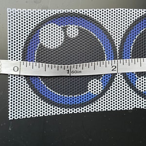 May include: A close-up of a white mesh fabric with two blue and black circles printed on it. The fabric is measured with a ruler, showing 1 1/2 inches.
