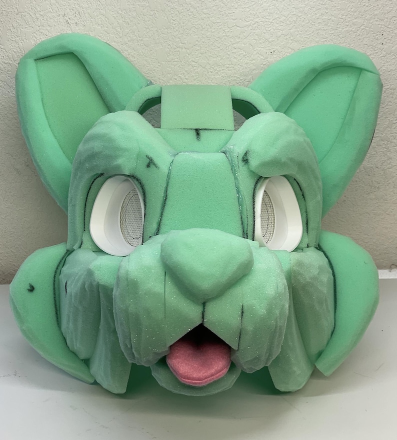 May include: Green foam base for a furry costume head with white eye sockets and a pink tongue.