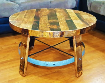 May include: A round wooden coffee table with a reclaimed barrel top and a metal base. The table has a rustic, industrial look and is perfect for a living room or den.