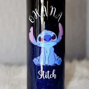 May include: A blue and black glitter tumbler with a white design that says "Ohana" and "Stitch". The tumbler features a cartoon image of Stitch from the Disney movie Lilo & Stitch.
