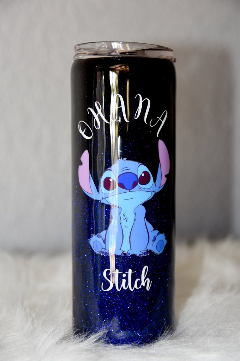 May include: A blue and black glitter tumbler with a white design that says "Ohana" and "Stitch". The tumbler features a cartoon image of Stitch from the Disney movie Lilo & Stitch.